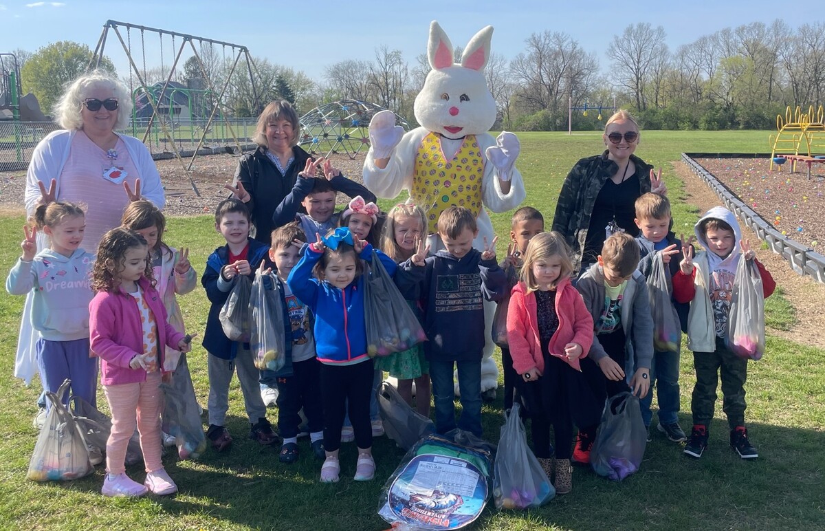 Preschool students and teachers on a playground with the Easter Bunny.